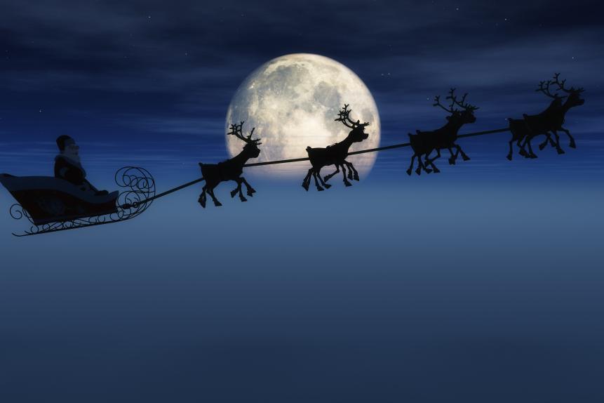 Santa on his sleigh pulled by 8 reindeer in front of a large moon and fog.