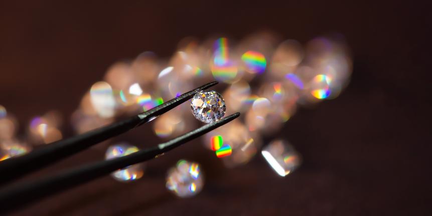 Diamond with tweezers and magnifier.reflections on the ground. brilliant cut diamond held by tweezers.Gemstone Beauty