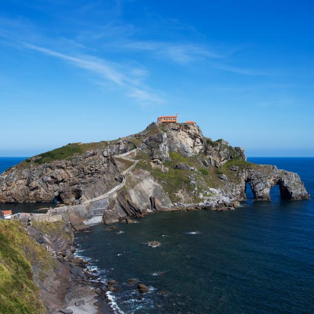 Gaztelugatxe is an islet on the coast of Biscay, Spain. It is connected to the mainland by a man-made bridge. On top of the island stands a church/ chapelle (named Gaztelugatxeko Doniene in Basque; San Juan de Gaztelugatxe in Spanish), dedicated to John the Baptist, that dates from the 10th century. The hermitage is accessed by a narrow path, crossing the solid stone bridge, and going up 237 steps.