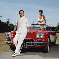 English comedian Paul Merton poses with a glamorous companion and a 1958 Chevrolet Corvette roadster, circa 1990. (Photo by Terry O'Neill/Iconic Images/Getty Images)