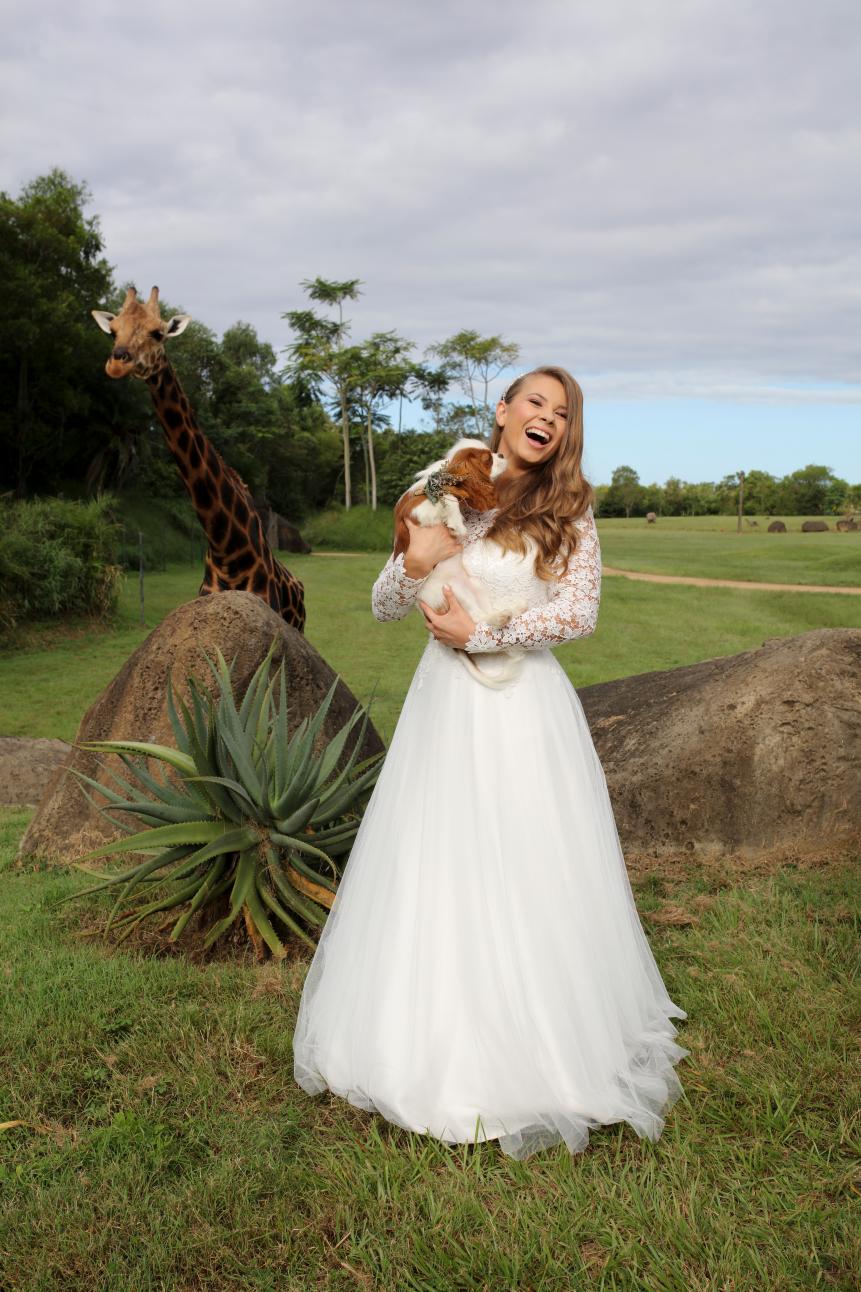 Bindi poses in her wedding dress with her puppy. Photography: Russell Shakespeare