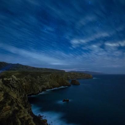 A single beam of light shines from a headlamp along the Cavern Point Trail as stars begin to come out, Santa Cruz Island, Channel Islands National Park, California.