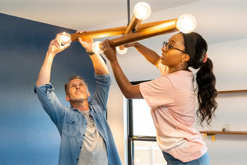 Photographer Ian Shive (left) screws in a lightbulb with Home Designer Kayla Simone (right) as part of a newly installed lighting fixture. Kayla is transforming a room into a home office in Pflugerville, Texas.