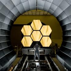 ERNIE WRIGHT STANDS NEAR THE JAMES WEBB SPACE TELESCOPE MIRRORS AS THEY SIT JUST OUTSIDE THE TESTING CHAMBER IN THE XRAY CALIBRATION FACILITY AT MSFC