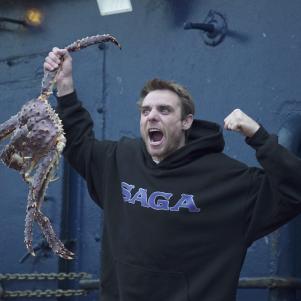 Captain Jake Anderson enthusiastically shows off a big King Crab aboard the Saga.