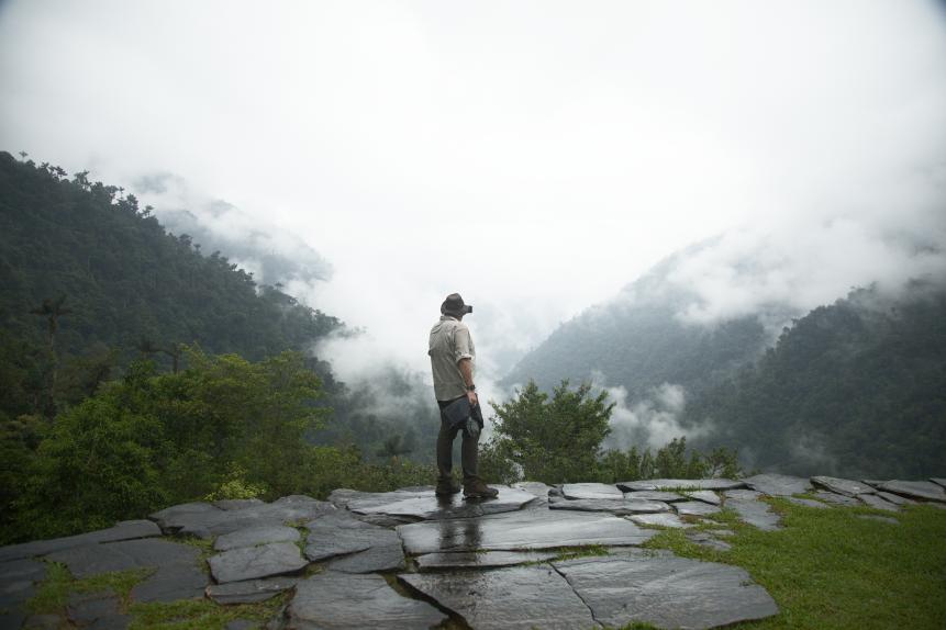 Josh Gates in front of a foggy valley on top of Ciudad Perdida