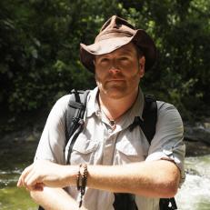 Josh Gates poses in a rushing river.