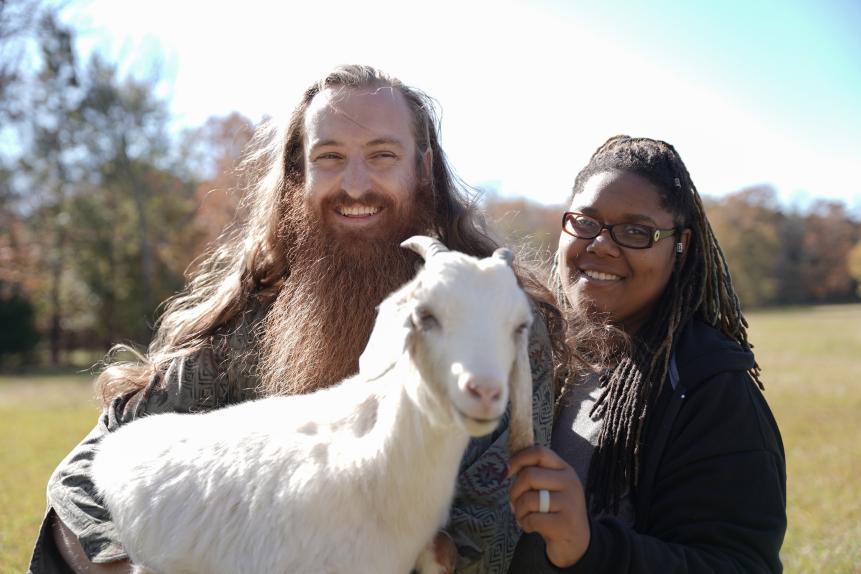 Joe Watts and Myesha Price smiling while holding a goat in Centre, AL.