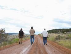 Chad Ollinger, Duane Ollinger, and Charlie Snider walk down the dirt road, away from camera, at Blind Frog Ranch.