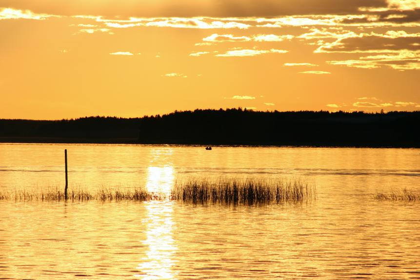 golden sun at midnight over lake in Finland