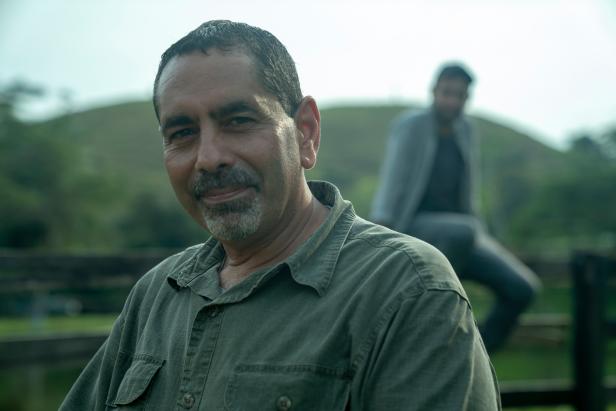 Jerry smiles at the camera with Ramon out of the focus in the background on a finca