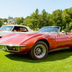 Ronneby, Sweden - July 17, 2014: Press show for upcoming event "Pony and muscle car meet". Corvette Stingray 1969 convertible parked on grass in Brunnsparken with old house in background.