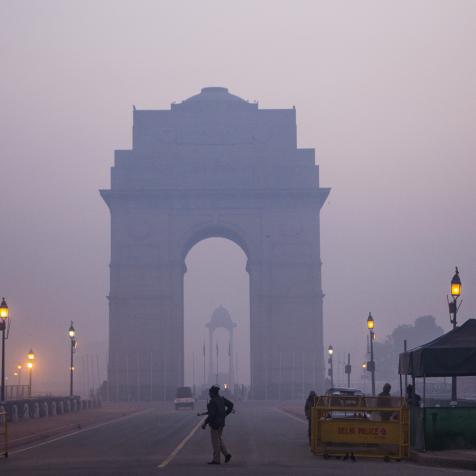 Police officers stand guard at the India Gate monument shrouded in smog in New Delhi, India. Photographer: Prashanth Vishwanathan/Bloomberg