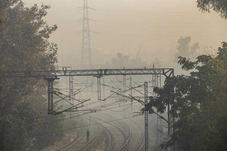 A pedestrian walks along rail tracks shrouded in smog in New Delhi, India. Photographer: Prashanth Vishwanathan/Bloomberg