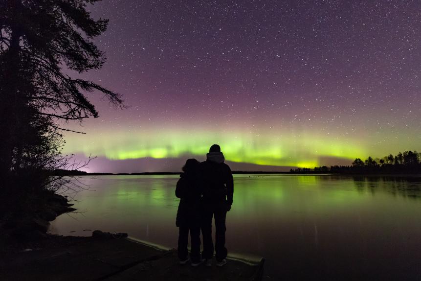 Couple looking at Northern Lights over Lake Kuusamo, Pohjois-Pohjanmaa, Finland