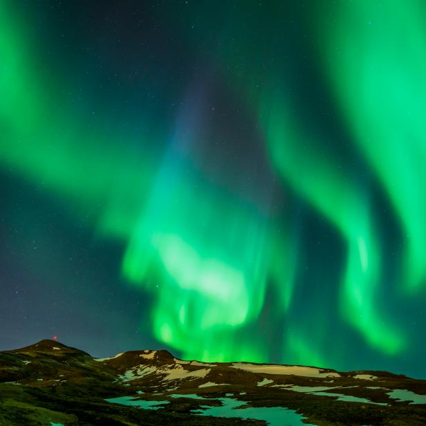 Northern lights shining bright in the arctic winter, Mt. Ulfarsfell, Iceland