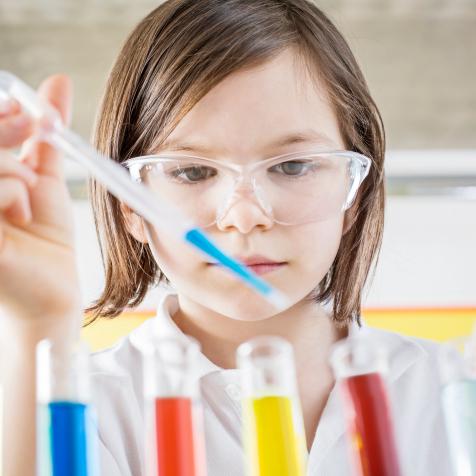 Girl(10-11) in school laboratory conducting a scientific experiment colored liquids in test tubes using a pipette, School Science Project,Ideas,Imagination,Laboratory Coat,chemistry, Discovery,Education,Enjoyment,test tubes, science project, Pipette,Chemistry,Confidence