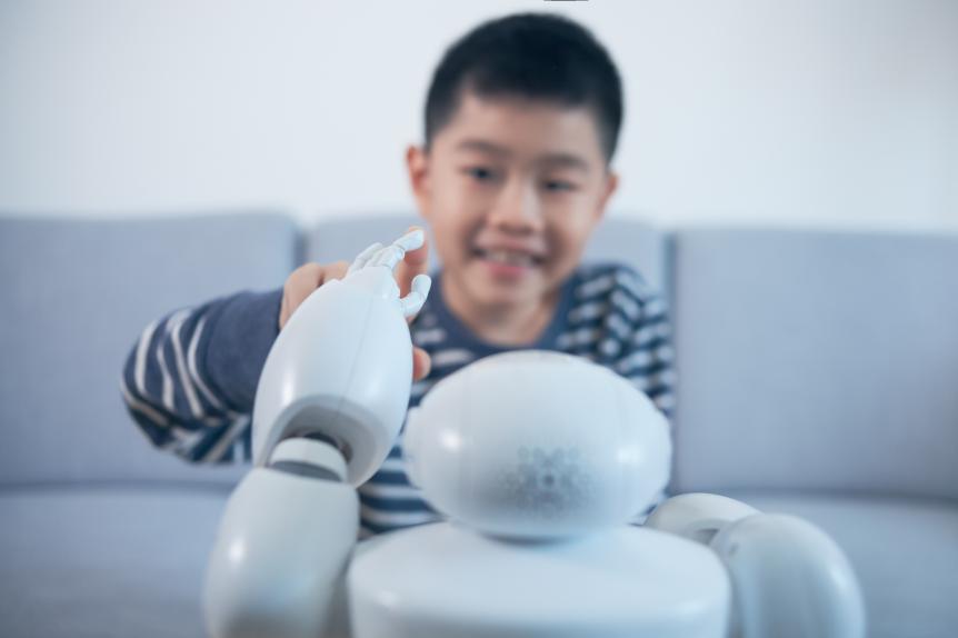 Smart boy touching robot finger indoors