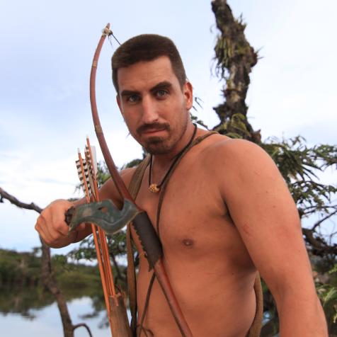 Matt poses with a bow and arrow.