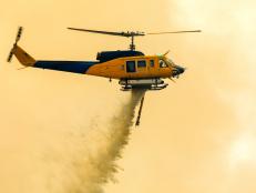 large Helicopter dropping water onto forest fires, burning in Ipswich, Australia on the 7th of December 2019