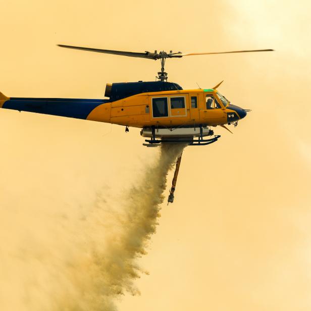 large Helicopter dropping water onto forest fires, burning in Ipswich, Australia on the 7th of December 2019