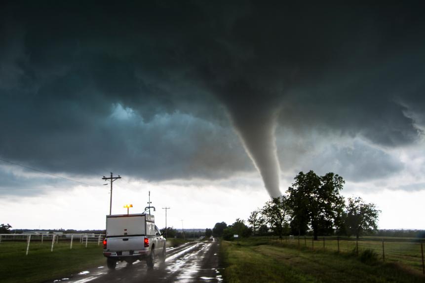 A research vehicle plunges down the road ahead of the tornado to deploy scientific instruments.