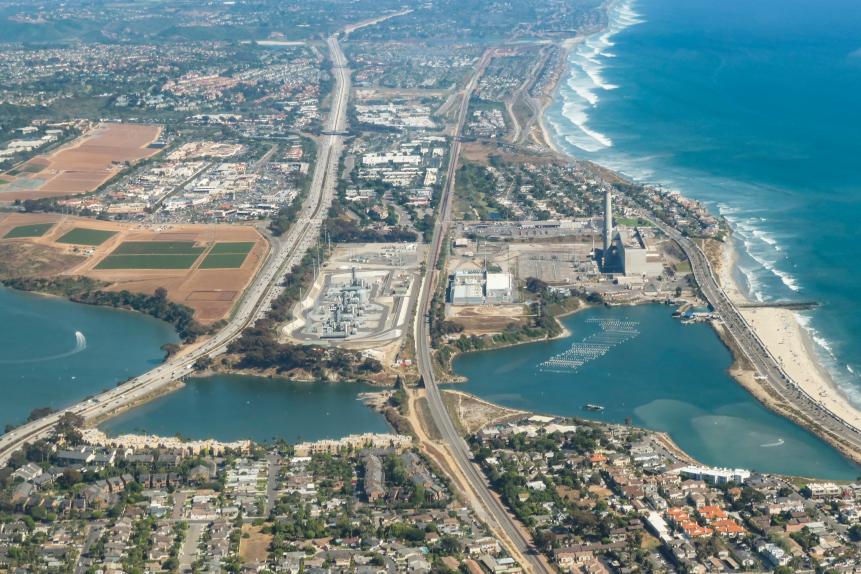 Lagoon and surrounding area from the air, including power plant / smoke stack, desalination plant. I-5 and the 101 separate the lagoon into 3 areas. This lagoon is the only Carlsbad lagoon where water sports are permitted. Agricultural patches of green on left side are strawberry fields.
