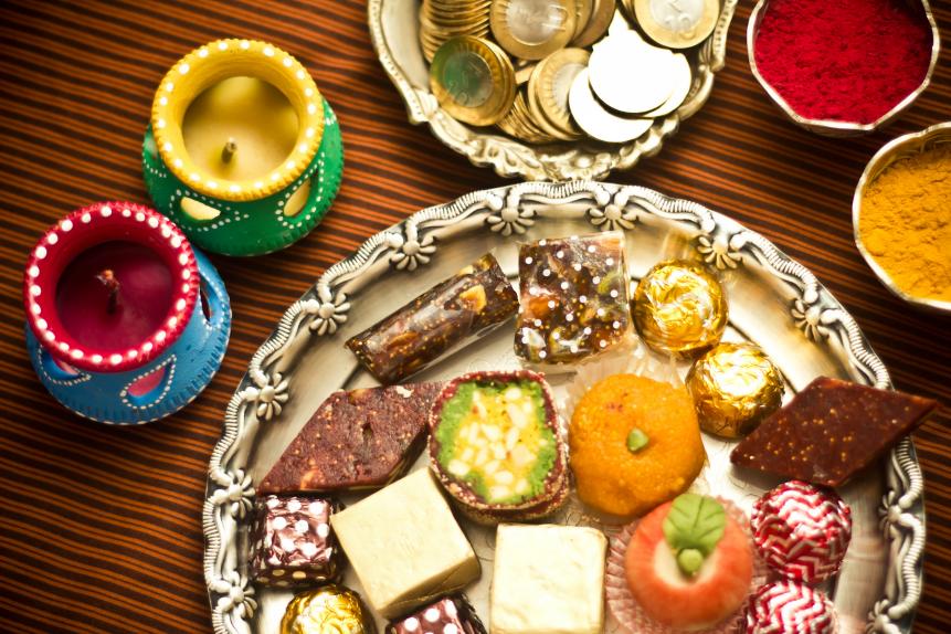 Diwali festive preparations with a plate of sweets ,diyas,money,kumkum and haldi.