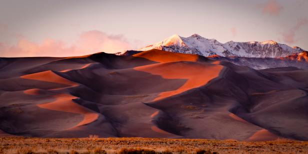 Sand dunes and mountain peaks lit with evening light. Great Sand Dune National Park, Alamosa, Colorado.