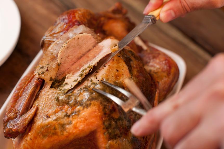 Closeup view from above of a man carving a tasty Thanksgiving roast turkey slicing the breast with a carving knife
