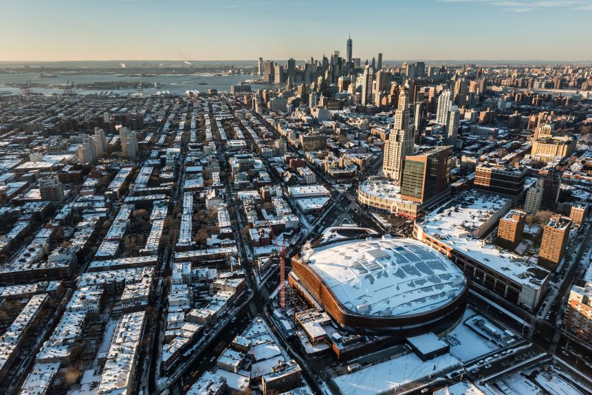 Aerial over Brooklyn close to the Barclay Center with Manhattan in the background during the winter in the snow at the end of the day