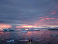 ILULISSAT, GREENLAND - SEPTEMBER 04: People watch the sunset as rain falls in the distance beyond floating ice and icebergs in Disko Bay on September 04, 2021 in Ilulissat, Greenland. 2021 will mark one of the biggest ice melt years for Greenland in recorded history. Researchers from Denmark estimated that in July of this year enough ice melted on the Greenland Ice Sheet to cover the entire state of Florida with two inches of water. According to NASA, Greenland has melted 5 trillion tons of ice over approximately the past 15 years, enough to increase global sea level by nearly an inch. The observations come on the heels of the recent United Nations report on global warming which stated that accelerating climate change is driving an increase in extreme weather events. (Photo by Mario Tama/Getty Images)