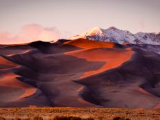 Sand dunes and mountain peaks lit with evening light. Great Sand Dune National Park, Alamosa, Colorado.