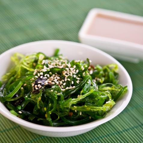 Wakame seaweed salad with nut sauce, garnished with sesame seeds and red chili pepper