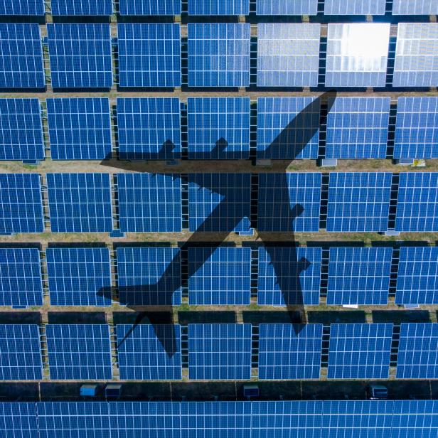 Aerial view/The shadow of a plane flying over a solar farm located on the farm to receive sunlight for electricity.
