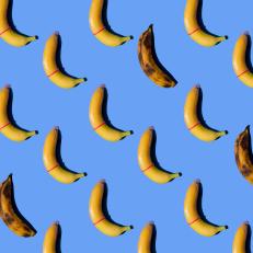 Banana with condom on blue background.