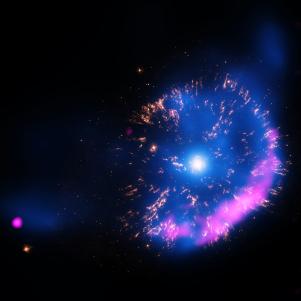 In Hollywood blockbusters, explosions are often among the stars of the show. In space, explosions of actual stars are a focus for scientists who hope to better understand their births, lives, and deaths and how they interact with their surroundings.  Using NASA’s Chandra X-ray Observatory, astronomers have studied one particular explosion that may provide clues to the dynamics of other, much larger stellar eruptions.    A team of researchers pointed the telescope at GK Persei, an object that became a sensation in the astronomical world in 1901 when it suddenly appeared as one of the brightest stars in the sky for a few days, before gradually fading away in brightness. Today, astronomers cite GK Persei as an example of a “classical nova,” an outburst produced by a thermonuclear explosion on the surface of a white dwarf star, the dense remnant of a Sun-like star.  A nova can occur if the strong gravity of a white dwarf pulls material from its orbiting companion star.  If enough material, mostly in the form of hydrogen gas, accumulates on the surface of the white dwarf, nuclear fusion reactions can occur and intensify, culminating into a  cosmic-sized hydrogen bomb blast. The outer layers of the white dwarf are  blown away, producing a nova outburst that can be observed for a period of months to years as the material expands into space.  Classical novas can be considered to be “miniature” versions of supernova explosions. Supernovas signal the destruction of an entire star and can be so bright that they outshine the whole galaxy where they are found. Supernovas are extremely important for cosmic ecology because they inject huge amounts of energy into the interstellar gas, and are responsible for dispersing elements such as iron, calcium and oxygen into space where they may be incorporated into future generations of stars and planets.  Although the remnants of supernovas are much more massive and energetic than classical novas, some of the fundamental physics is the same. Both involve an explosion and creation of a shock wave that travels at supersonic speeds through the surrounding gas.    The more modest energies and masses associated with classical novas means that the remnants evolve more quickly. This, plus the much higher frequency of their occurrence compared to supenovas, makes classical novas important targets for studying cosmic explosions.  Chandra first observed GK Persei in February 2000 and then again in November 2013. This 13-year baseline provides astronomers with enough time to notice important differences in the X-ray emission and its properties.  This new image of GK Persei contains X-rays from Chandra (blue), optical data from NASA’s Hubble Space Telescope (yellow), and radio data from the National Science Foundation’s Very Large Array (pink). The X-ray data show hot gas and the radio data show emission from electrons that have been accelerated to high energies by the nova shock wave. The optical data reveal clumps of material that were ejected in the explosion. The nature of the point-like source on the lower left is unknown.  Over the years that the Chandra data span, the nova debris expanded at a speed of about 700,000 miles per hour. This translates to the blast wave moving about 90 billion miles during that period.  One intriguing discovery illustrates how the study of nova remnants can provide important clues about the environment of the explosion. The X-ray luminosity of the GK Persei remnant decreased by about 40% over the 13 years between the Chandra observations, whereas the temperature of the gas in the remnant has essentially remained constant, at about one million degrees Celsius. As the shock wave expanded and heated an increasing amount of matter, the temperature behind the wave of energy should have decreased. The observed fading and constant temperature suggests that the wave of energy has swept up a negligible amount of gas in the environment around the star over the past 13 years. This suggests that the wave must currently be expanding into a region of much lower density than before, gi