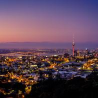 View of Auckland City including the Sky Tower and Harbour Bridge from Mount Eden at sunset.