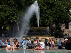 People cool off beside the fountains in Trafalgar Square in central London on June 17, 2022, on what is expected to be the hottest day of the year so far in the capital. - A Level 3 Heat-Health alert for London, the East of England and the South East has been announced to help protect health services, the UK Health Security Agency (UKHSA) has said, Friday. (Photo by CARLOS JASSO / AFP) (Photo by CARLOS JASSO/AFP via Getty Images)