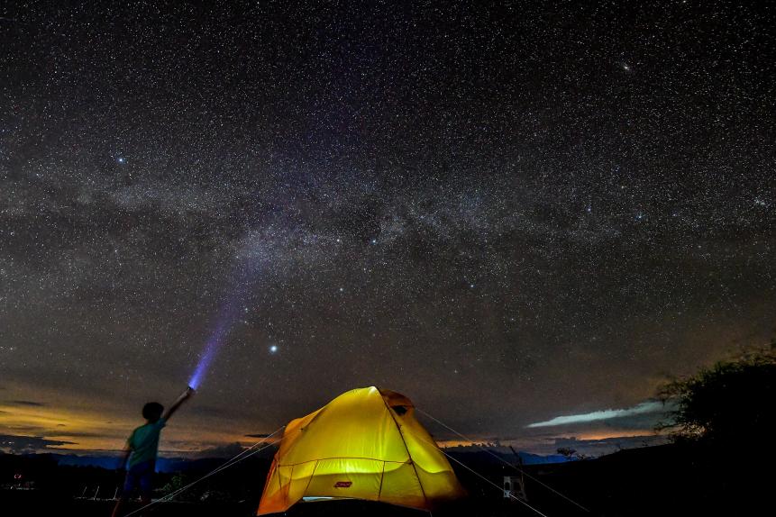 TOPSHOT - A boy watches the Milky Way in the sky over the Tatacoa Desert, in the department of Huila, Colombia, on October 11, 2018. (Photo by Luis ACOSTA / AFP)        (Photo credit should read LUIS ACOSTA/AFP via Getty Images)