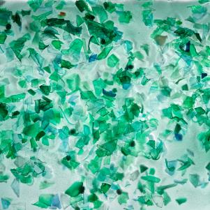 Small pieces of plastic from green PET bottles fished from the ocean. The plastic is frozen in a large block of ice. Photographed in 2018 the studio.