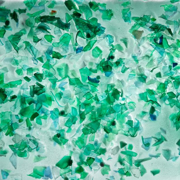 Small pieces of plastic from green PET bottles fished from the ocean. The plastic is frozen in a large block of ice. Photographed in 2018 the studio.