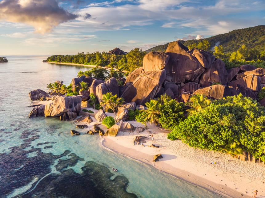 Picture of one of the most famous beach in the world, Anse Source d'Argent in Seychelles. It was taken at sunset , from a drone, with warm tones and gorgeous colors. Luxurious vegetation is seen all around, as well as the variations in sea's colors. Wonderful clouds seen.
Beach is known for its famous granite rock formations, white sand beach and turquoise waters.