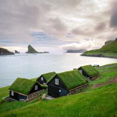 Turf-roofed houses near the small village of BÃ¸ur, with Drangarnir and TindhÃ³lmur on background. Faroe Islands