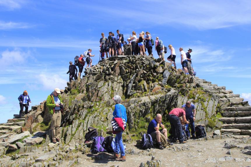 Walkers crowd onto the summit point, Mount Snowdon, Gwynedd, Snowdonia, north Wales, UK. (Photo by: Geography Photos/Universal Images Group via Getty Images)